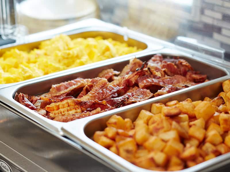 Complimentary hot buffet breakfast at Brendel’s Bagels in Long Island, NY featuring a fresh spread of New York–style bagels, scrambled eggs, crispy bacon, hash browns all served in the morning