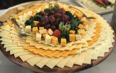 A beautifully arranged cheese platter from Brendel’s Bagels in Long Island, NY, featuring an assortment of fresh cheeses, sliced fruits, crackers, and garnishes, perfect for catering and special events.