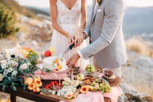 The bride and groom smiling as they cut into a beautifully decorated wedding cake at their Long Island, NY reception, with Brendel’s Bagels providing the celebration catering.